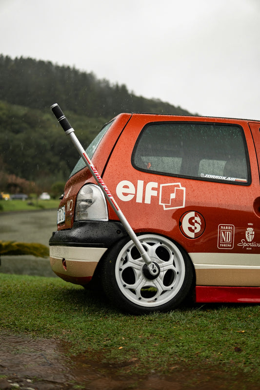 Orange car with custom wheels and stickers parked on grass